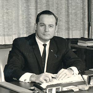 1960's photo of President Don Montgomery seated at his desk.