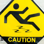 Yellow caution sign portraying a black stick figure falling on a wet floor.