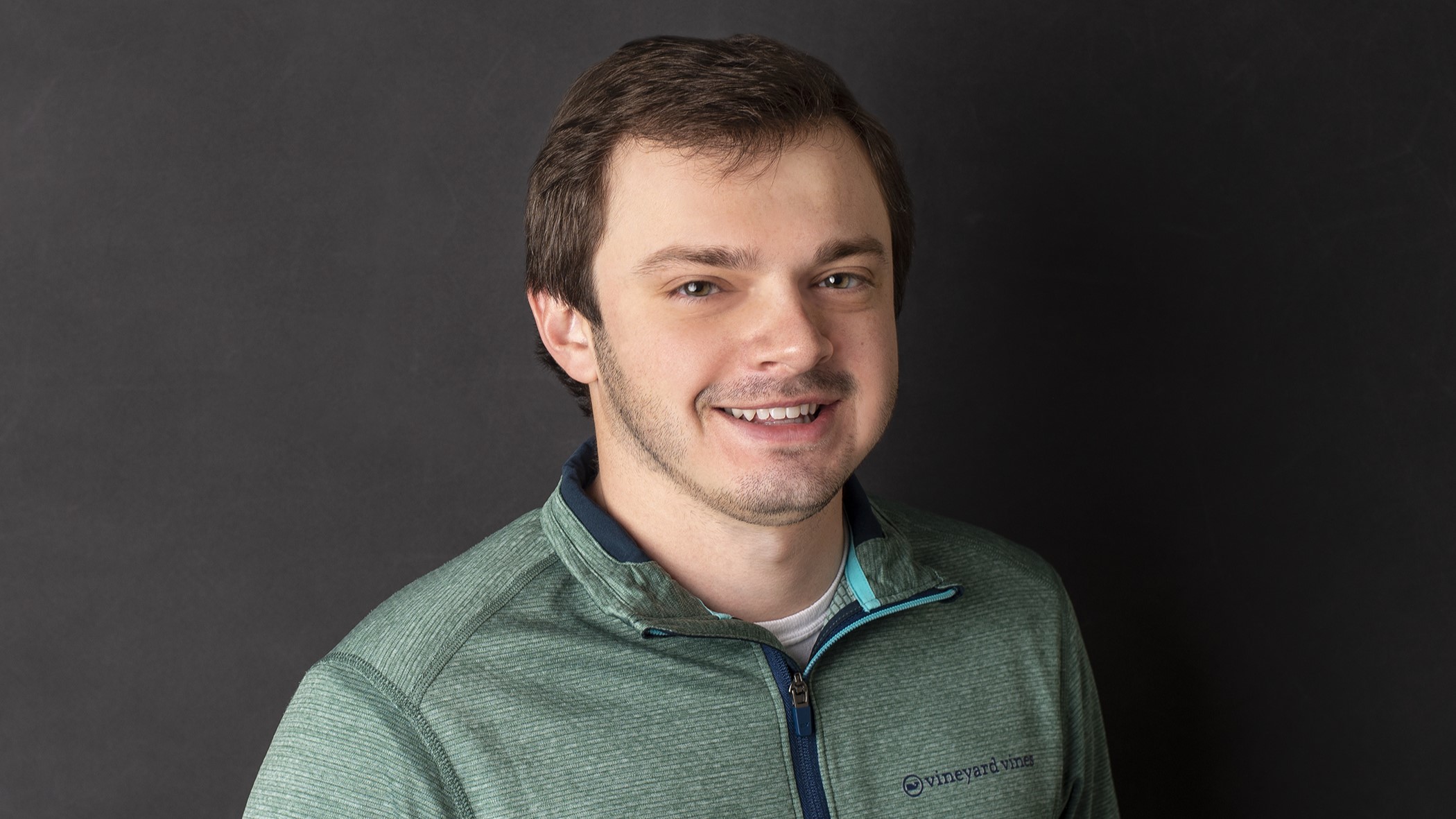 Brayton Adams, Associate Commercial Lines Underwriter at Celina Insurance Group, smiles in front of a dark gray background.