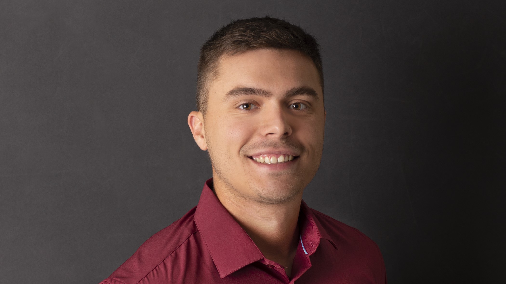 Brennan Meyers, Claims Representative Associate at Celina Insurance Group, smiles in front of a black background.