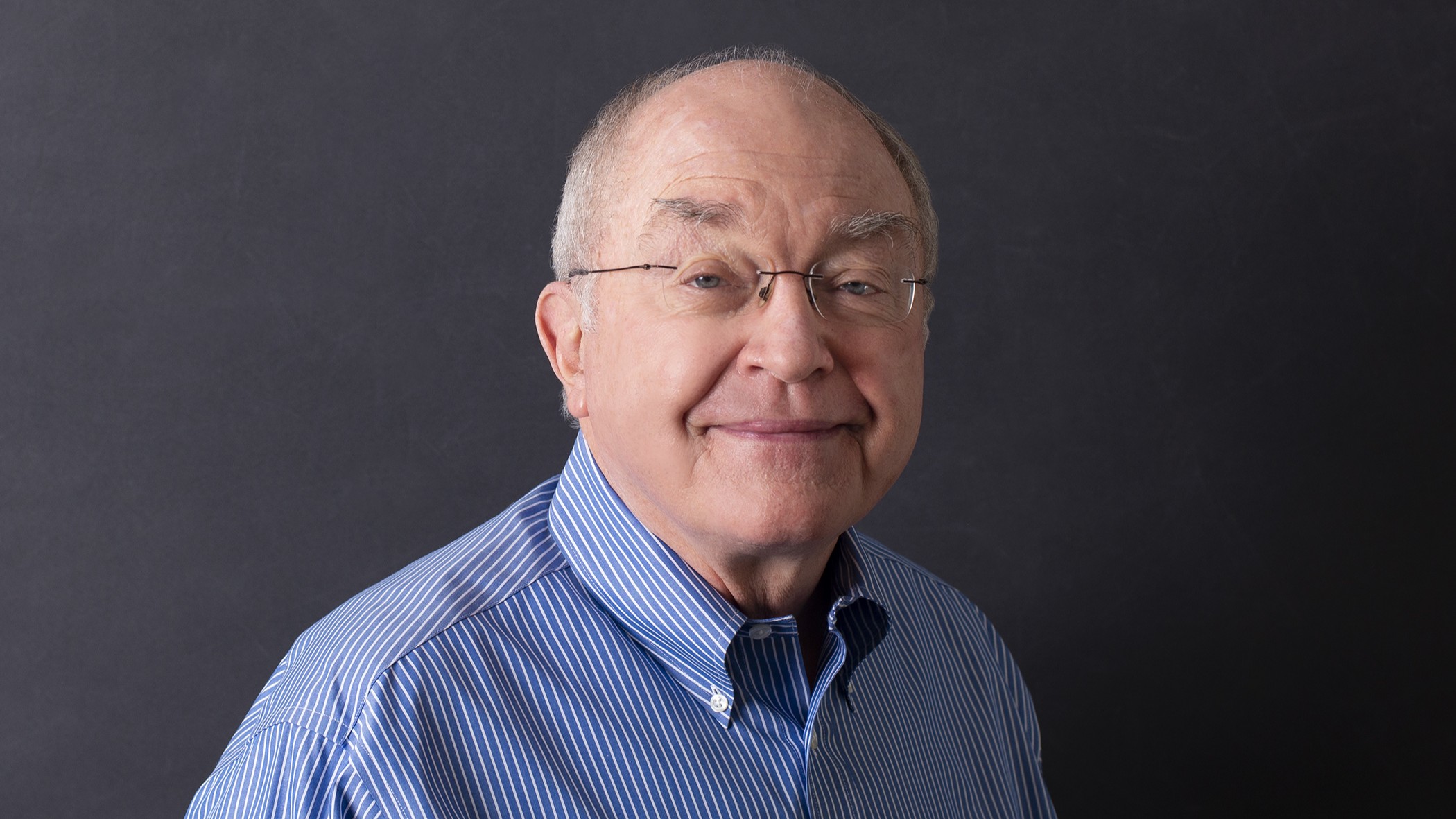 Craig Andrews, Senior Training Specialist at Celina Insurance Group, smiles in front of a black background.