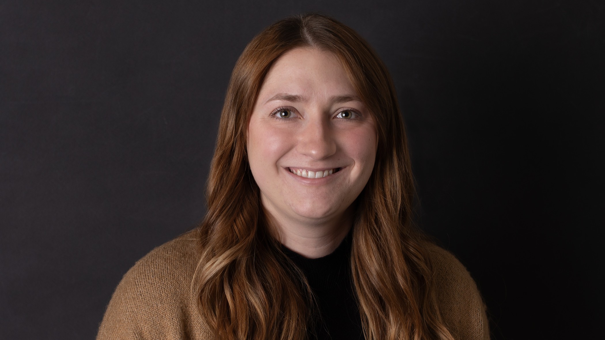 Devin Post, Commercial Underwriter at Celina Insurance Group, smiles in front of a black background.